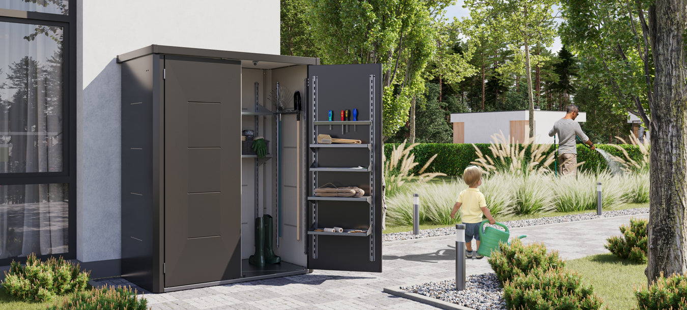 A Telluria Giarmadio cabinet open beside a house, showing shelves and garden tools stored inside