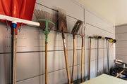 Inside a Telluria garage with the optional inside wall lining fitted, garden tools hung along the wall on the perforated plate