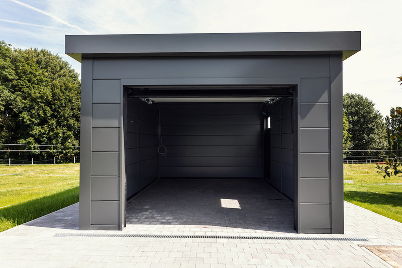 The same Telluria garage with the electric door open, showing the full 240cm by 200cm opening, the drainage channel across the threshold and the depth of the floor inside