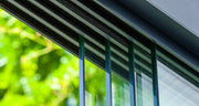 Close detail of the Telluria sliding door panels, showing the slim glass edges and the overlap where one panel slides past the next