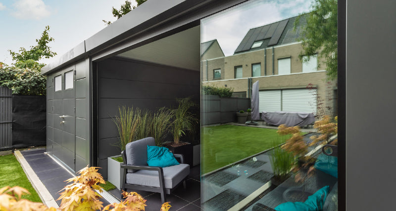 Telluria glass sliding doors closing in an open-fronted garden building, shown on a Classico rather than a Singolo: the panels run in a track set flush into the paving, with lounge seating inside