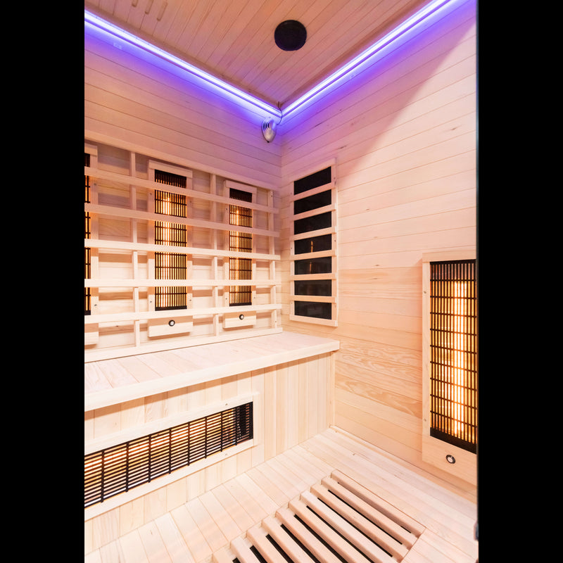 4 person far Infrared sauna with wooden walls and ceiling, illuminated by purple LED lights.