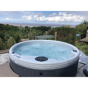 RotoSpa QuatroSpa 6 person hot tub with a coastal garden backdrop
