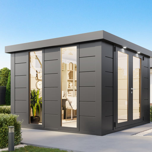 Anthracite Telluria Luminato 3030 steel garden room used as a home office, lit inside, on a paved base beside a house